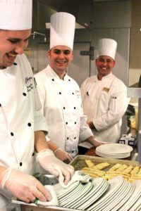 Three chefs smiling as they pose for photo